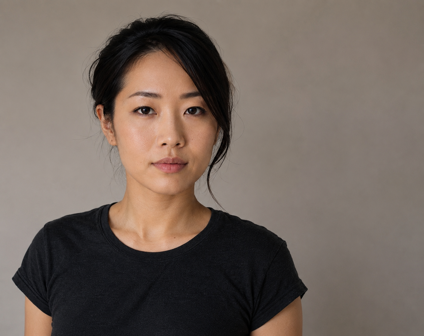 The SAME actor, same light, same crop, now standing roughly two metres out from the same wall. The head shadow has fallen away entirely; the wall has gone slightly darker and softer than the subject because the light has fallen off across the distance; there is visible separation between hair and wall. Show a small plan-view inset in the corner of each frame indicating the subject-to-wall distance, so the reader sees the cause.