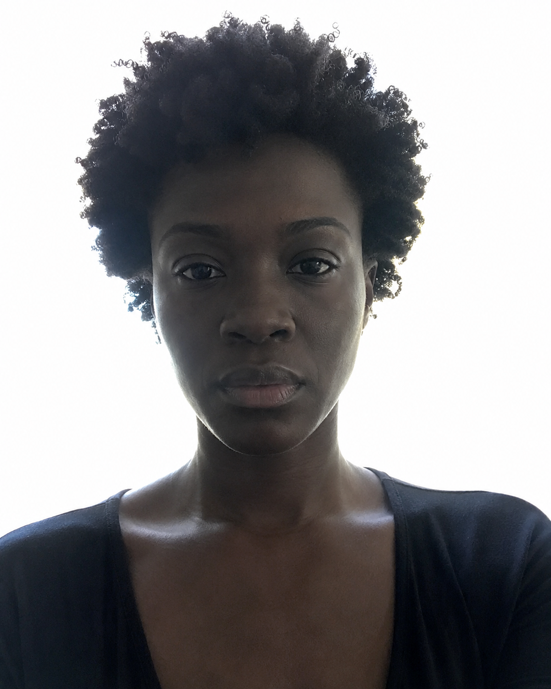 Real setup, real actor — ideally an actor with deeper skin, because this is where the failure is most consequential. Subject stands in front of a blown-out bright window or a hot white wall, camera left on auto-exposure. Result: background clipped to pure white, face underexposed, skin rendering grey/ashy and losing its natural warmth, catchlights weak, detail lost in the shadow side. Do not correct in post.