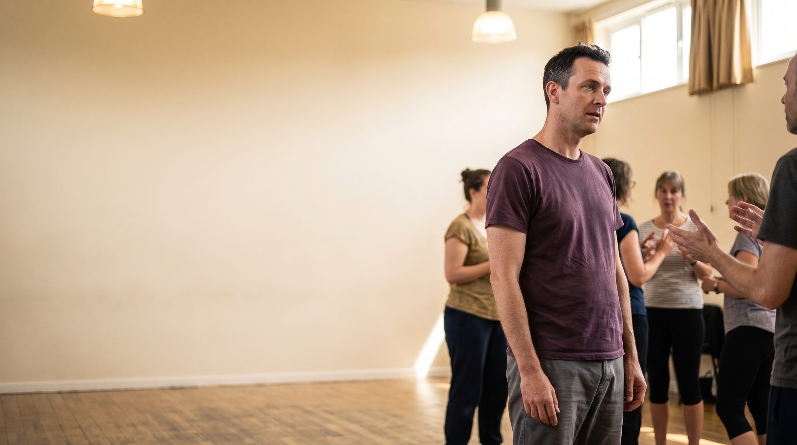 A beginner acting class in a community hall, students working in a loose semicircle