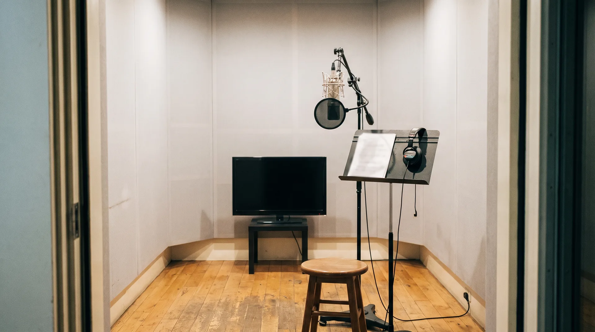 An empty dubbing booth with a music stand, a screen and a microphone waiting