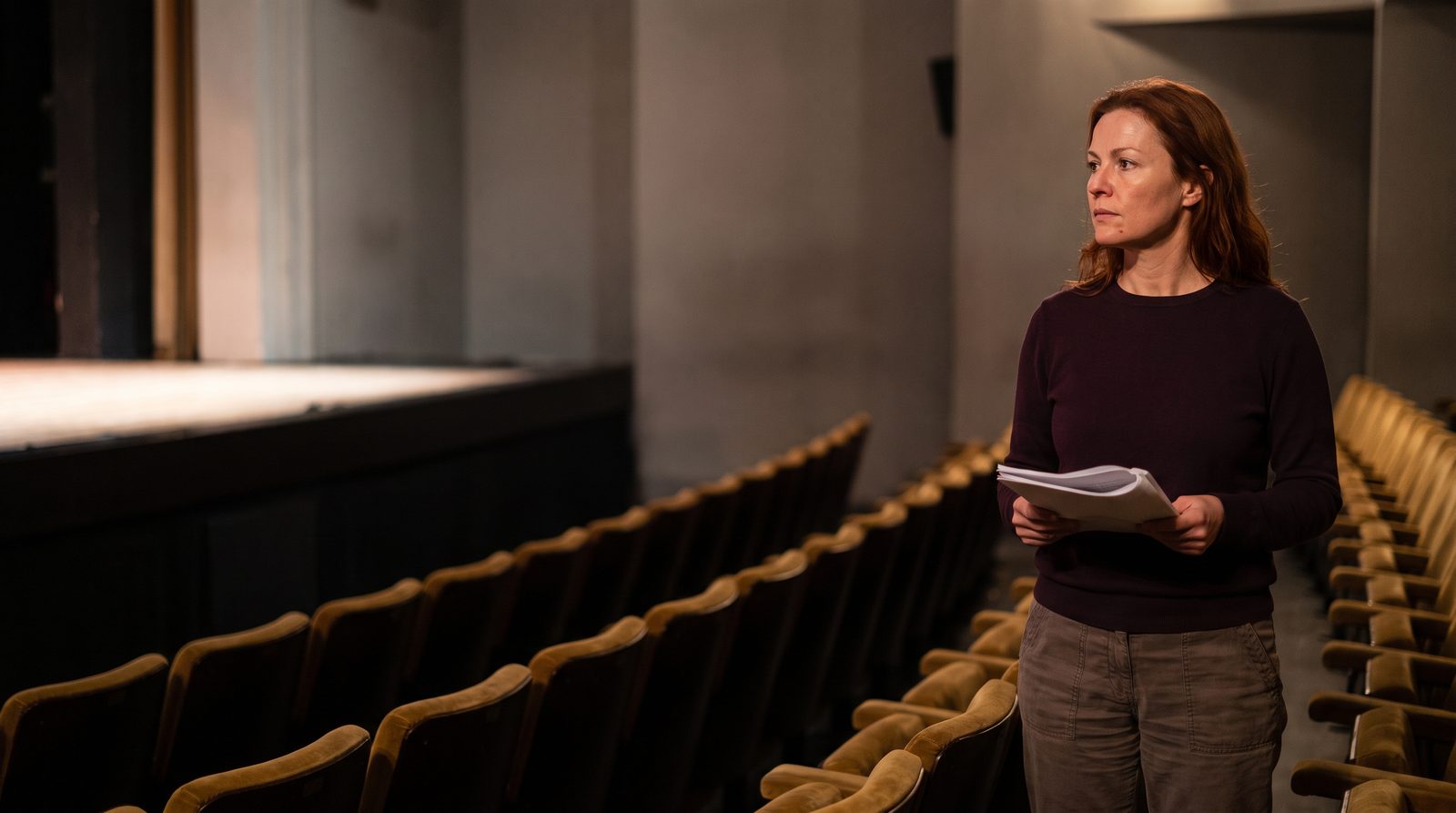 A new actor standing at the back of a small theatre, holding a script