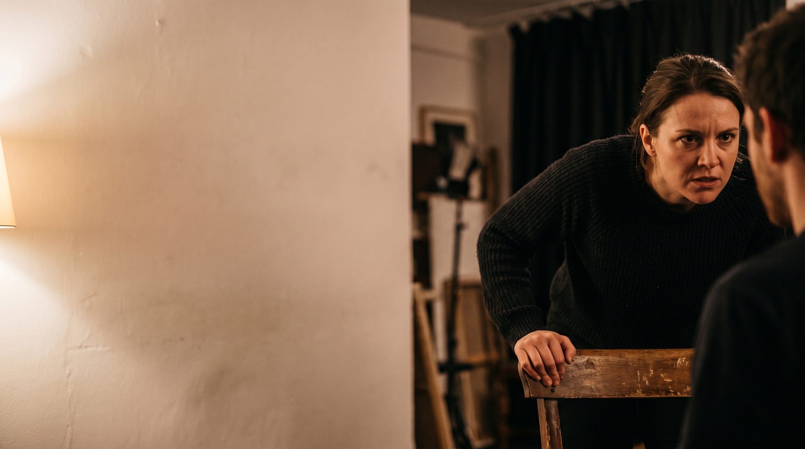 An actor mid-scene, leaning in toward an unseen partner with fierce focus