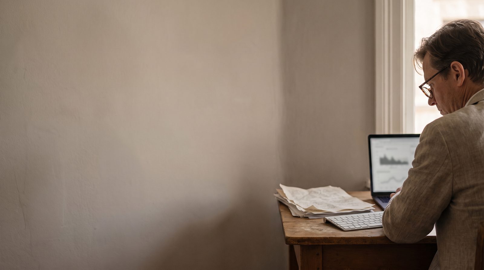 An actor at a desk reviewing performance footage on a laptop with script pages beside it