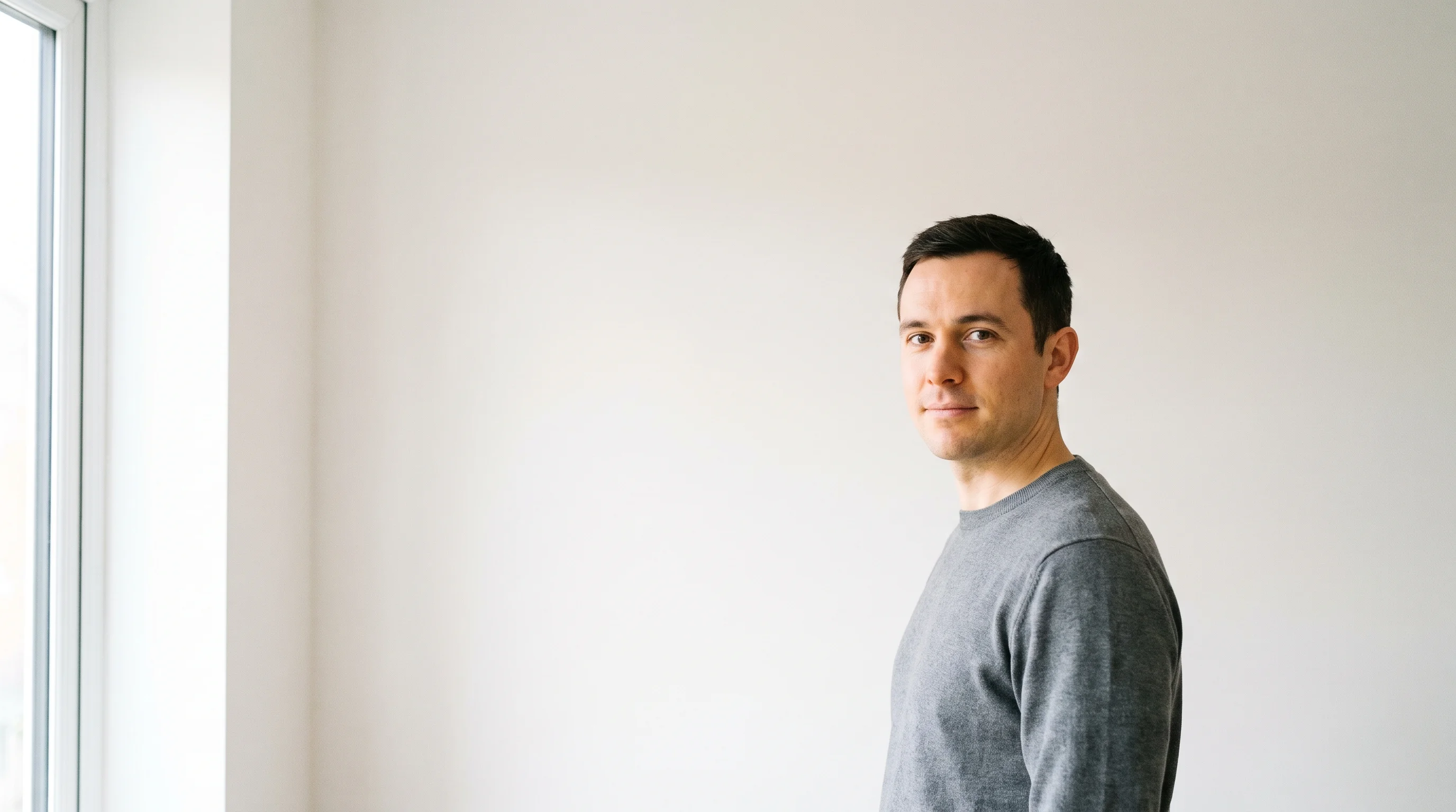 An actor standing in a bright room by a window, lit by daylight