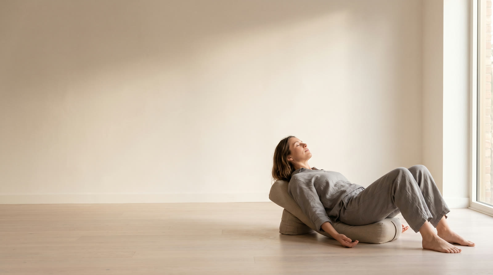 An actor lying back over a low support in a voice studio, ribs open, mid-breath