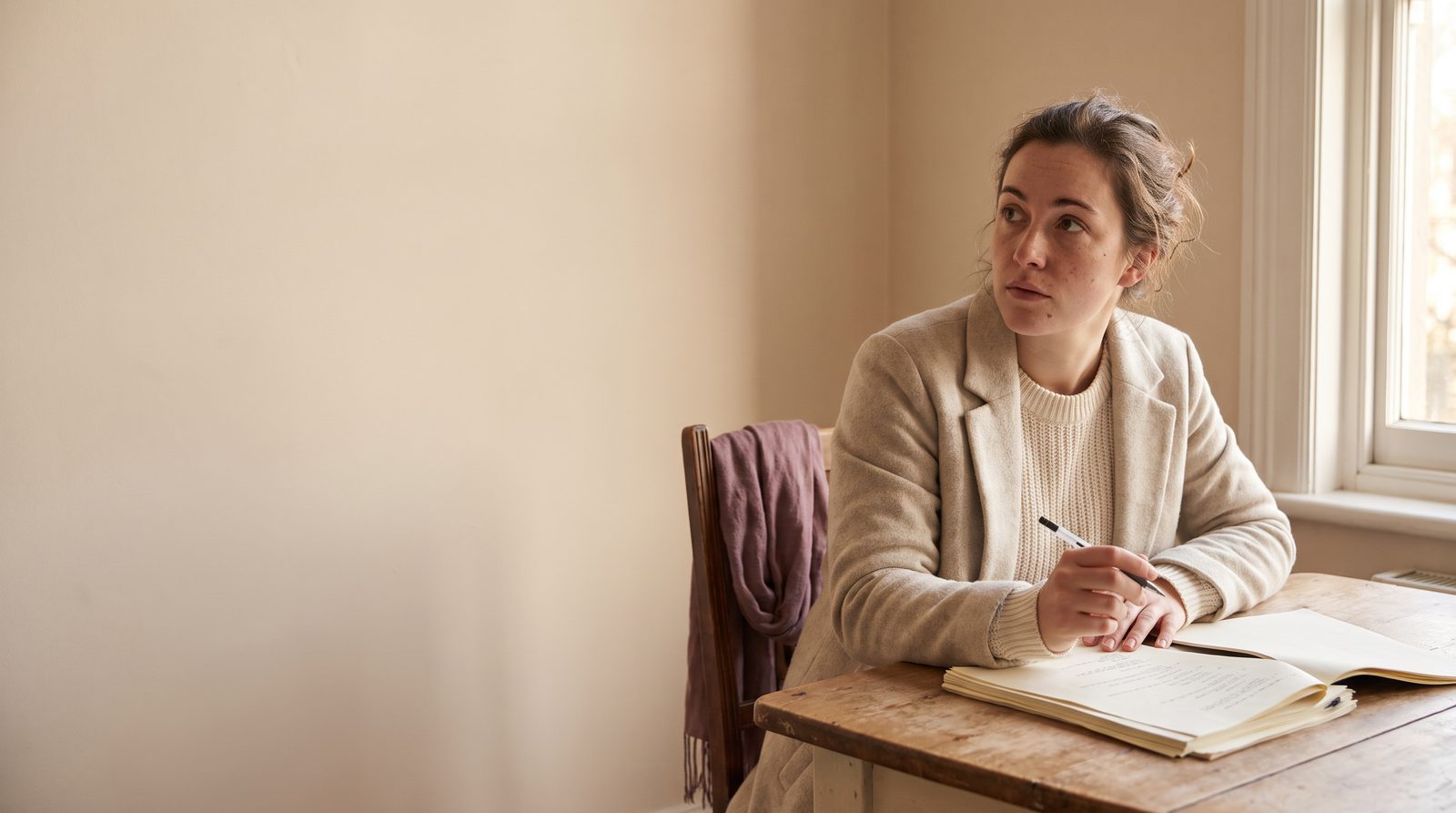 An actor at a table with script pages, looking up from the page