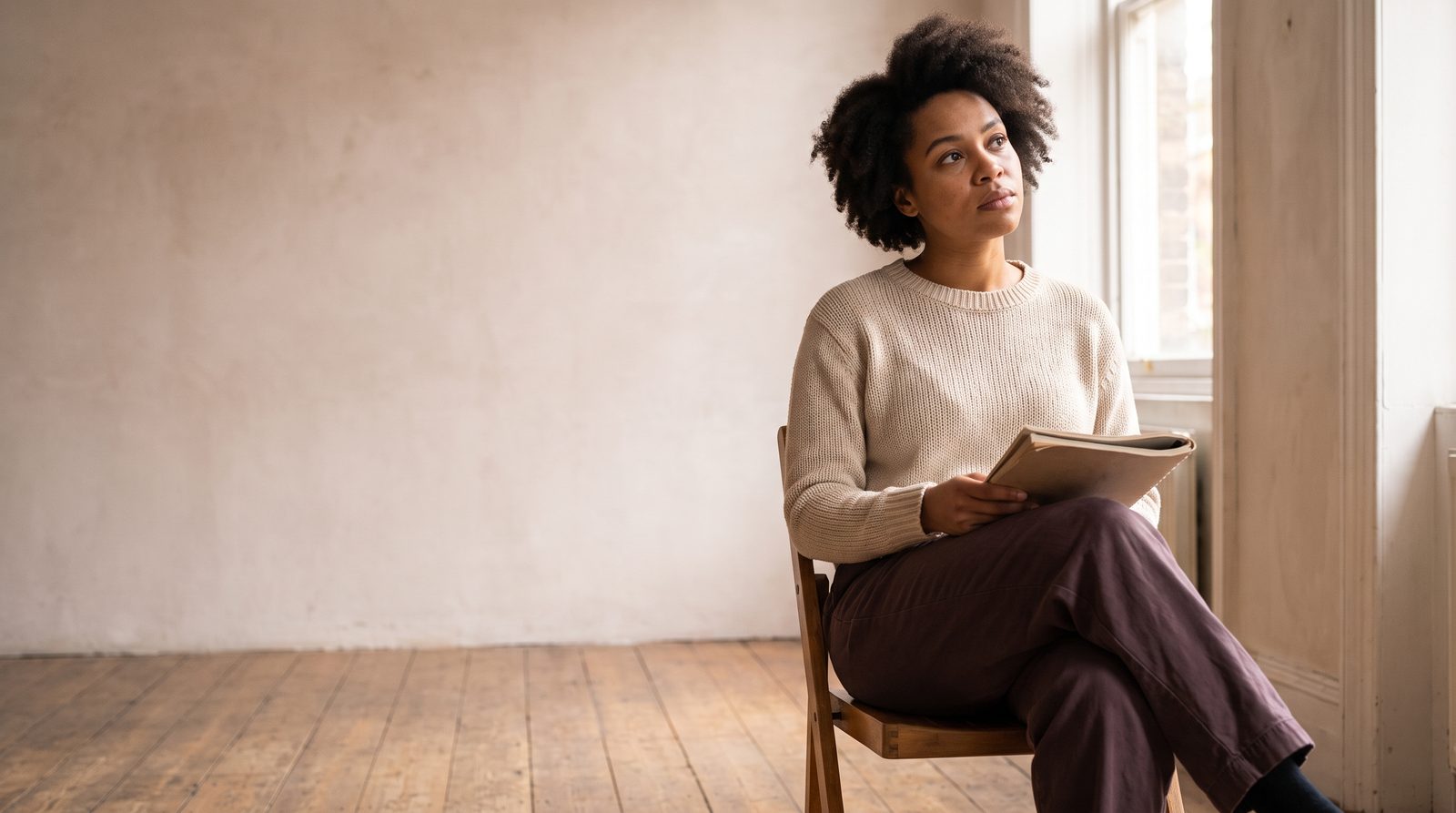 An actor sitting alone in a rehearsal room, thinking through a scene