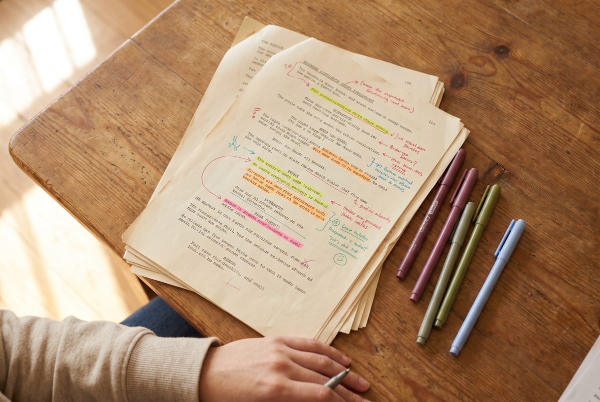 Script pages marked up by hand in coloured highlighter with drawn symbols in the margins