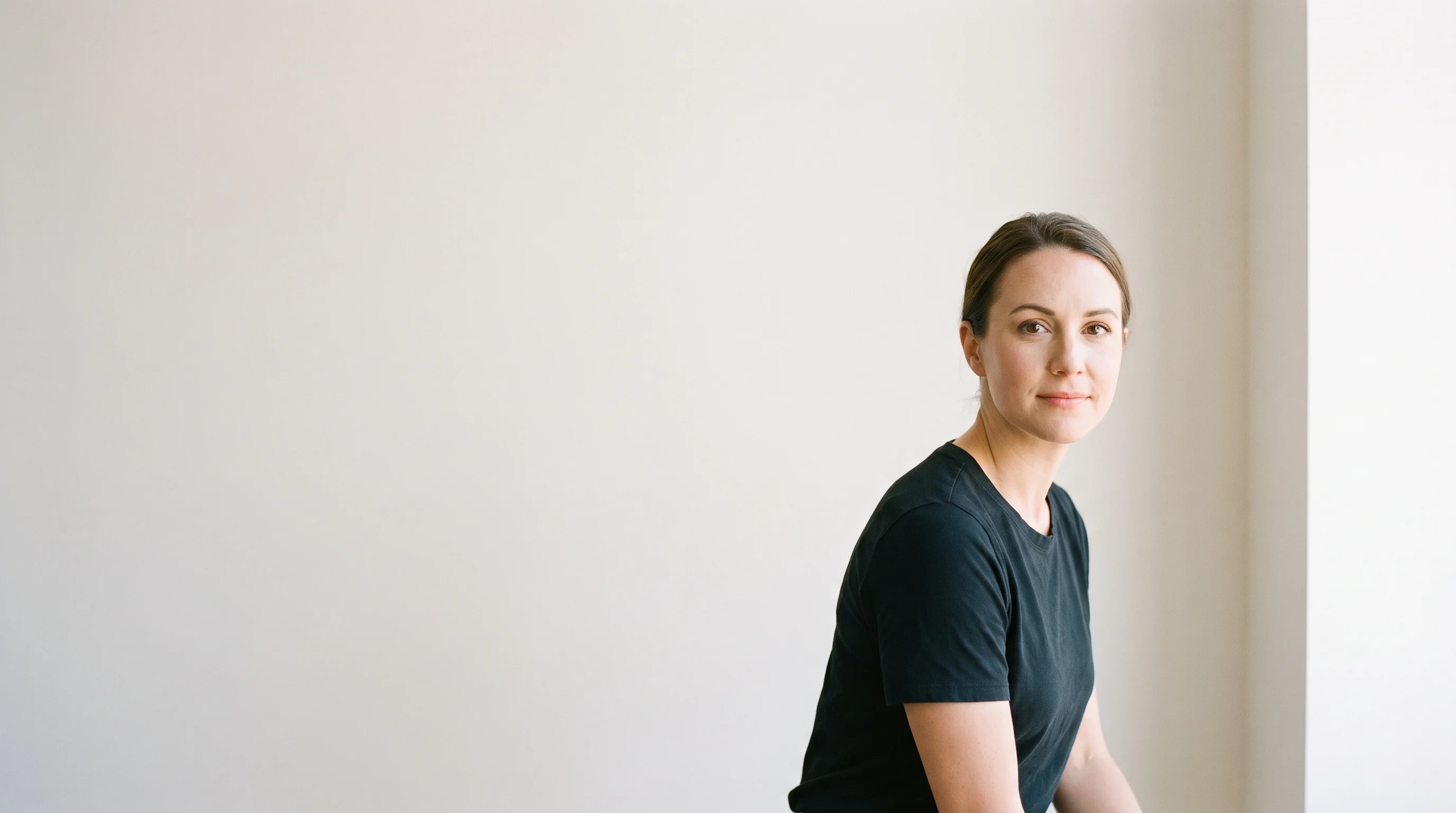 An actor standing against a plain studio wall during a headshot session