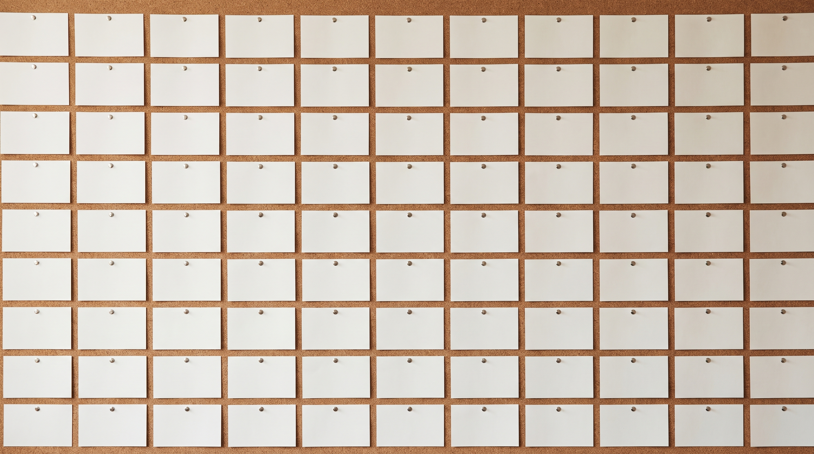 A grid of blank white index cards pinned in rows across a noticeboard