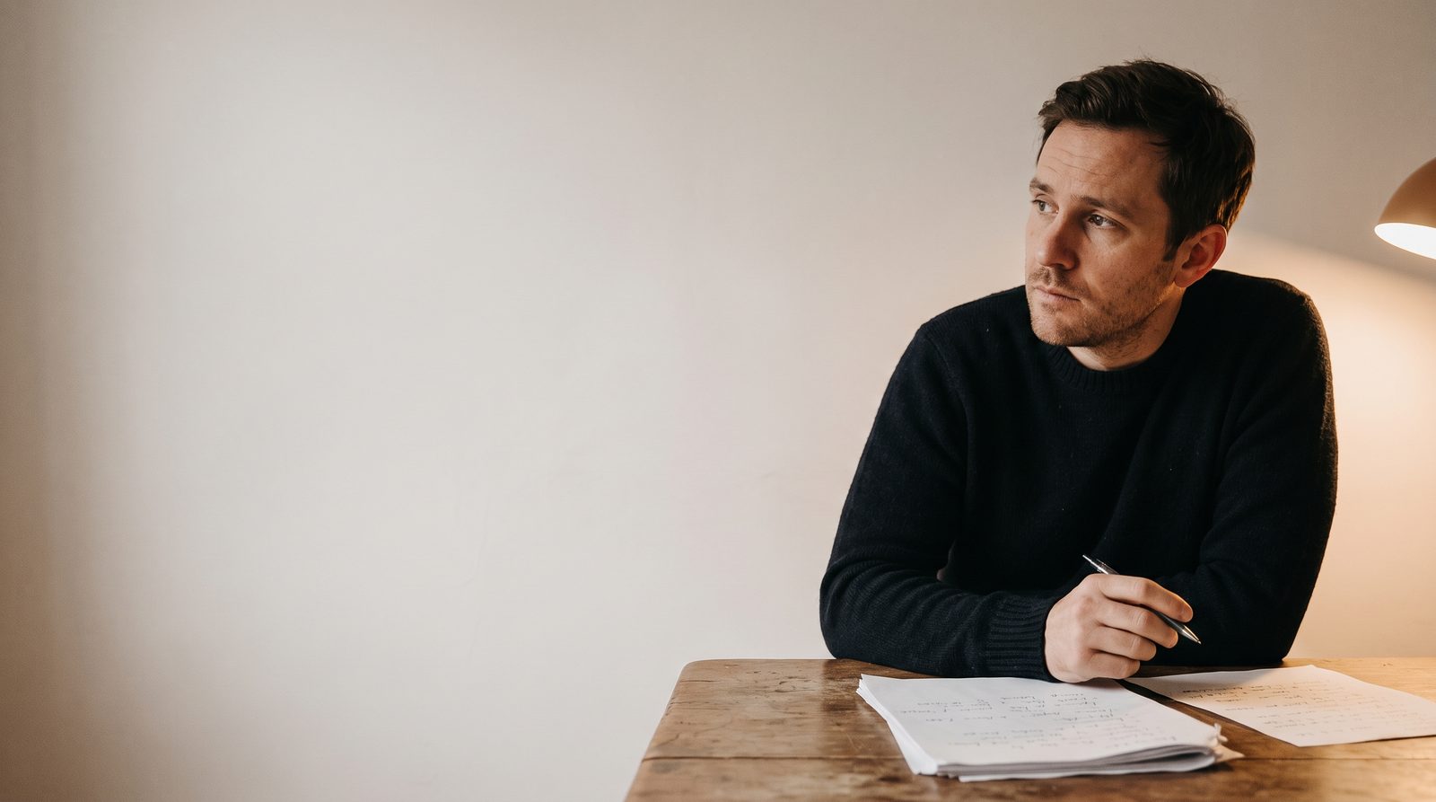 An actor at a table with marked-up script pages, thinking