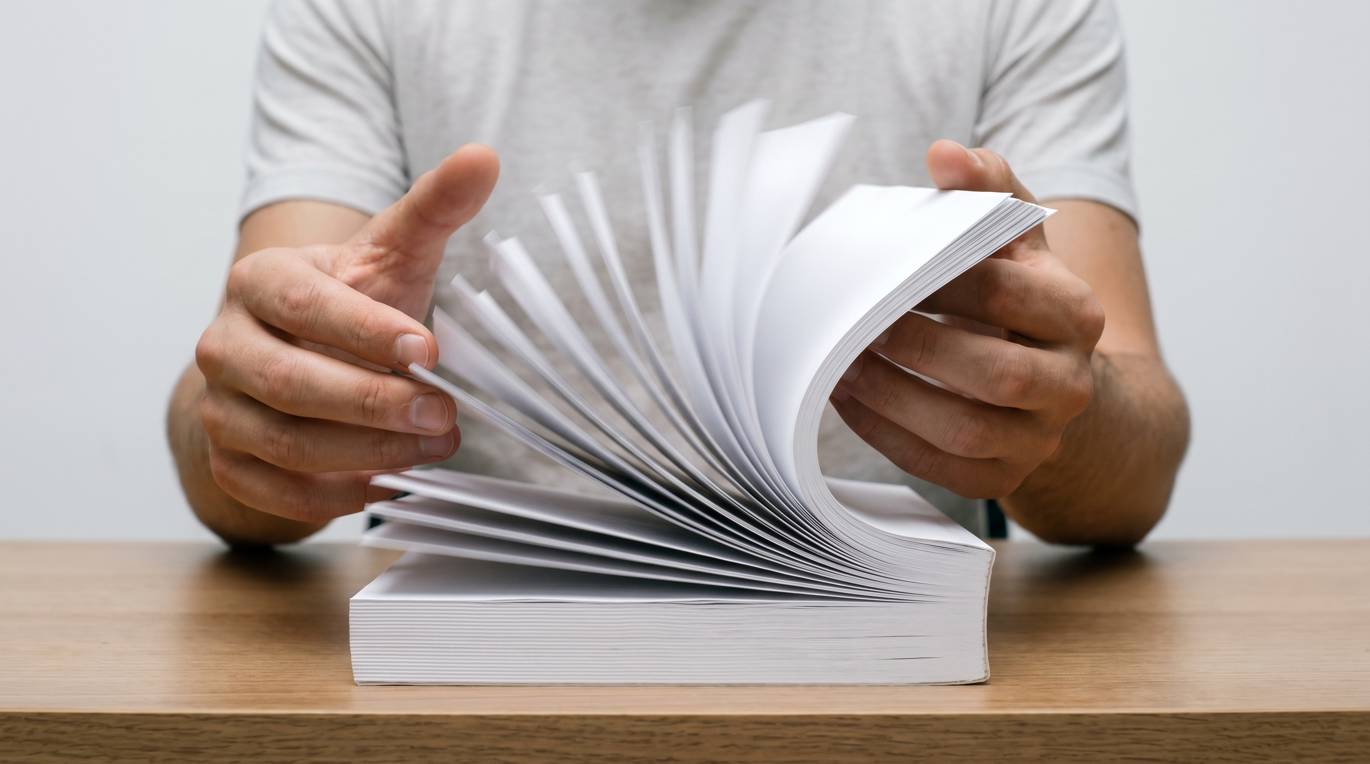 Hands flicking rapidly through a thick stack of blank white pages