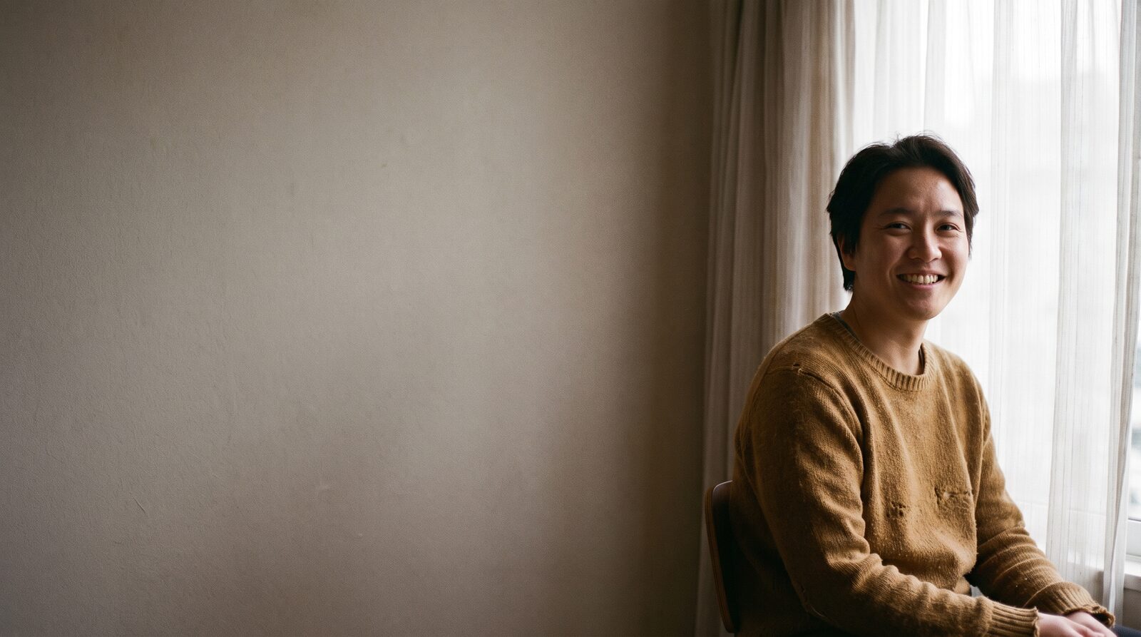 An actor sitting in soft daylight for a portrait, looking directly at the camera