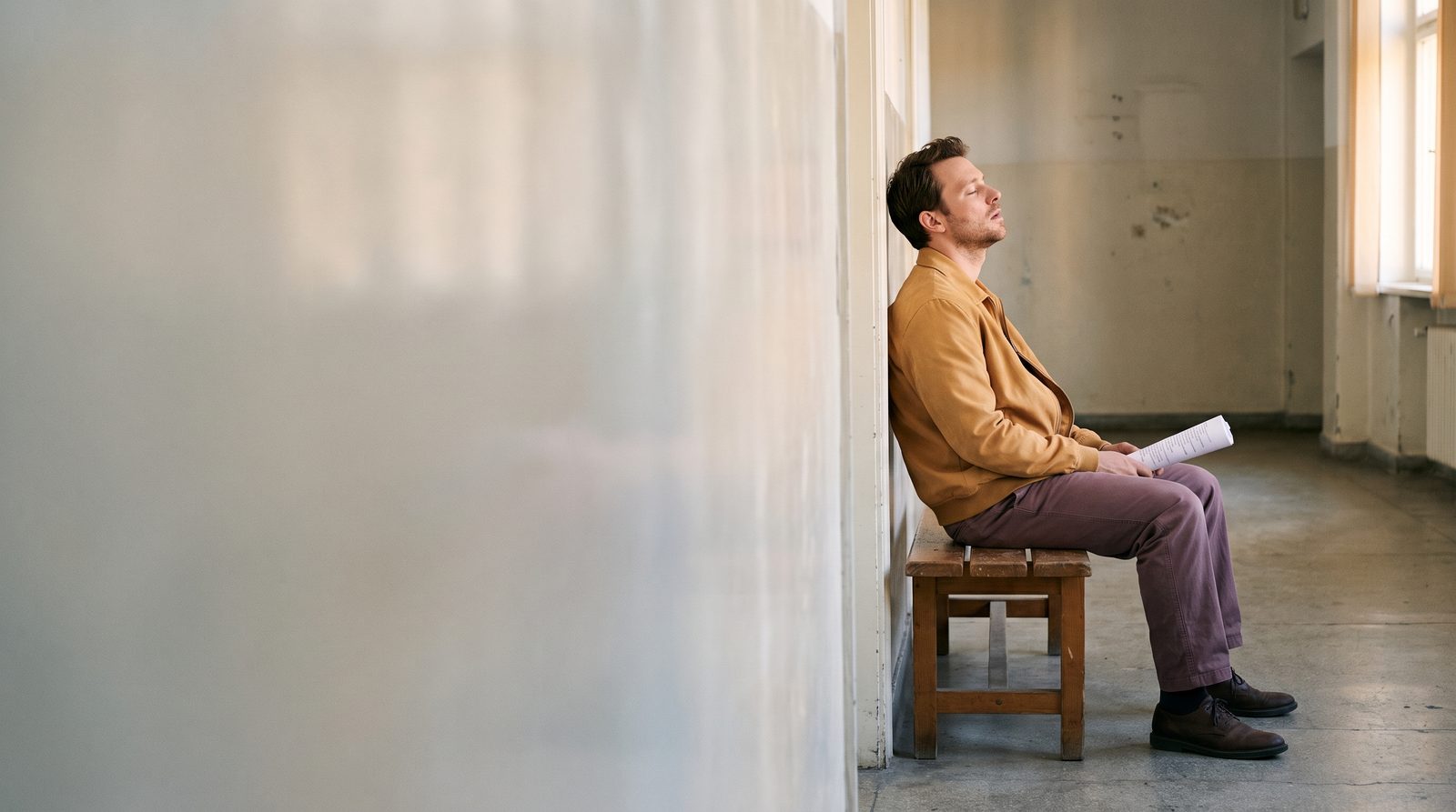 An actor waiting in a corridor before an audition, breathing out