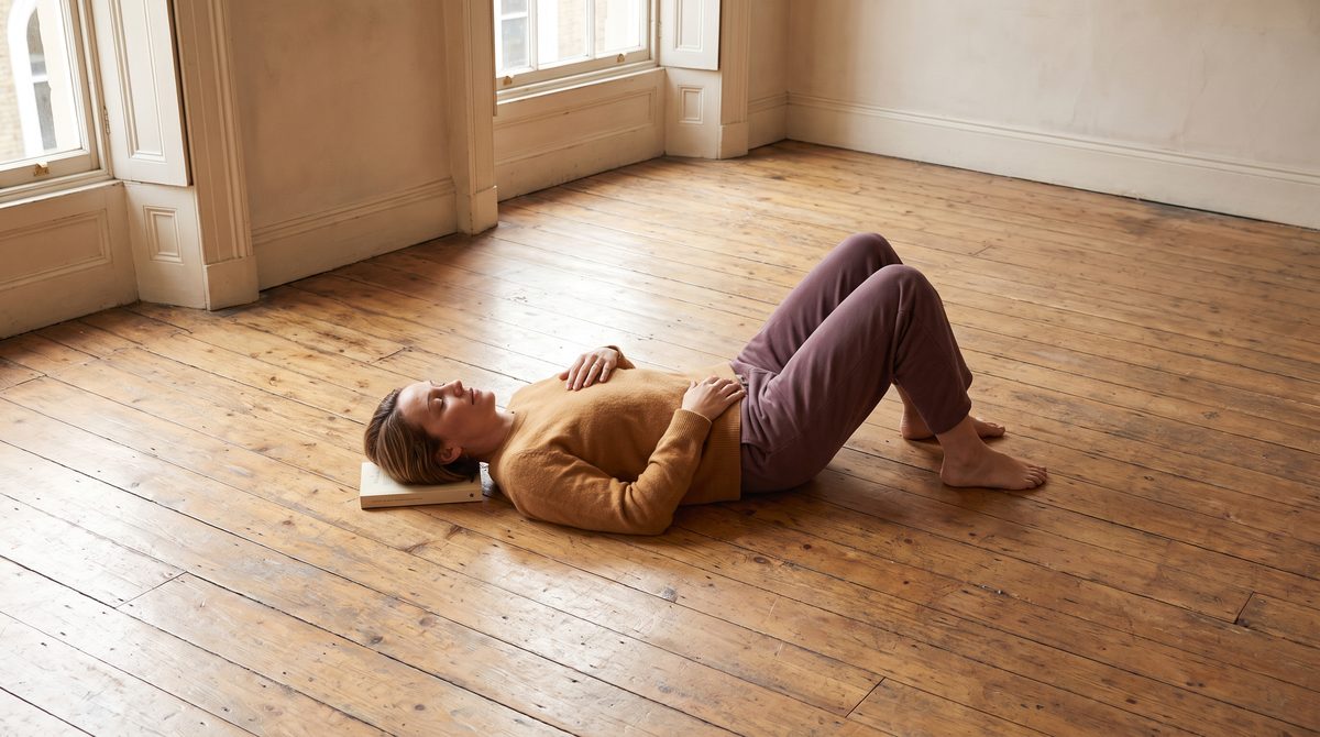 An actor lying in semi-supine constructive rest on a studio floor