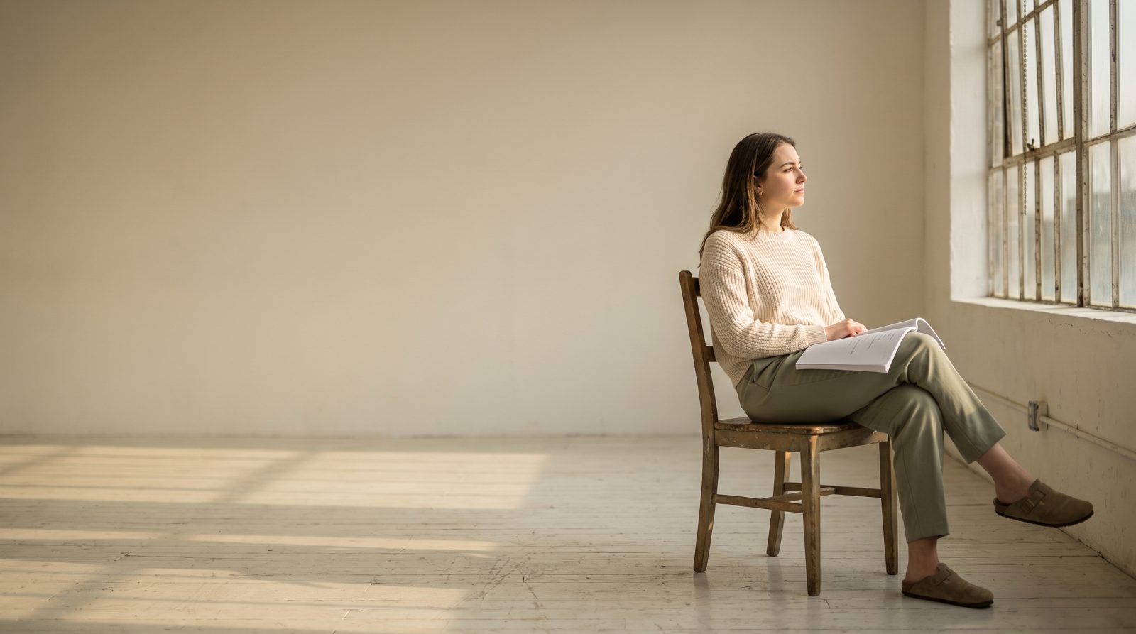 An actor sitting quietly at the edge of a rehearsal room after finishing work