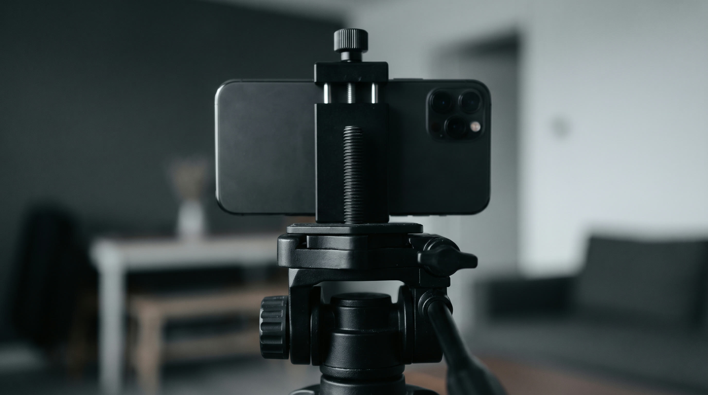 Close view from behind of a mobile phone clamped horizontally in landscape orientation on a tripod head
