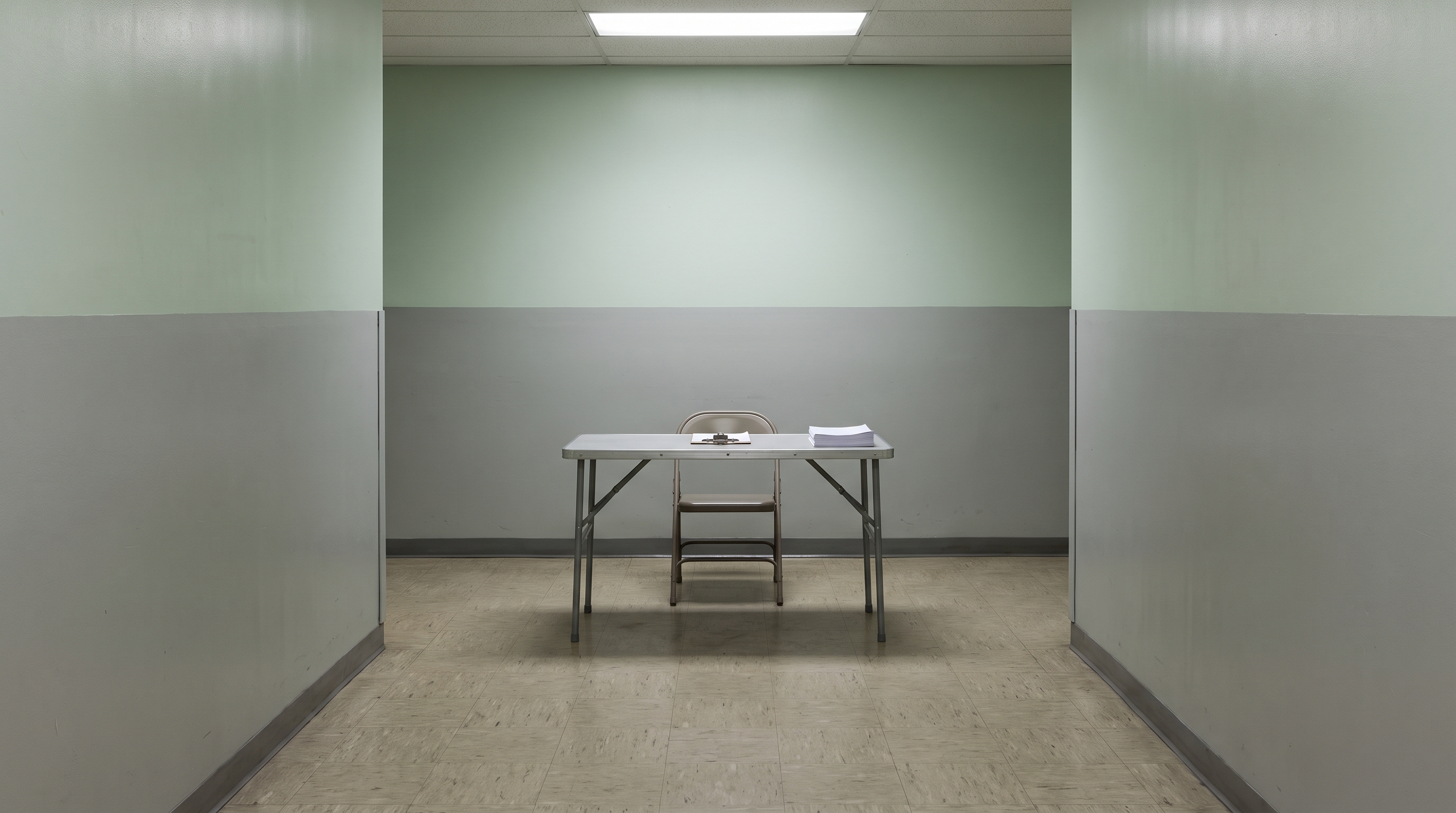 A folding table with a clipboard and a stack of blank papers in an empty corridor