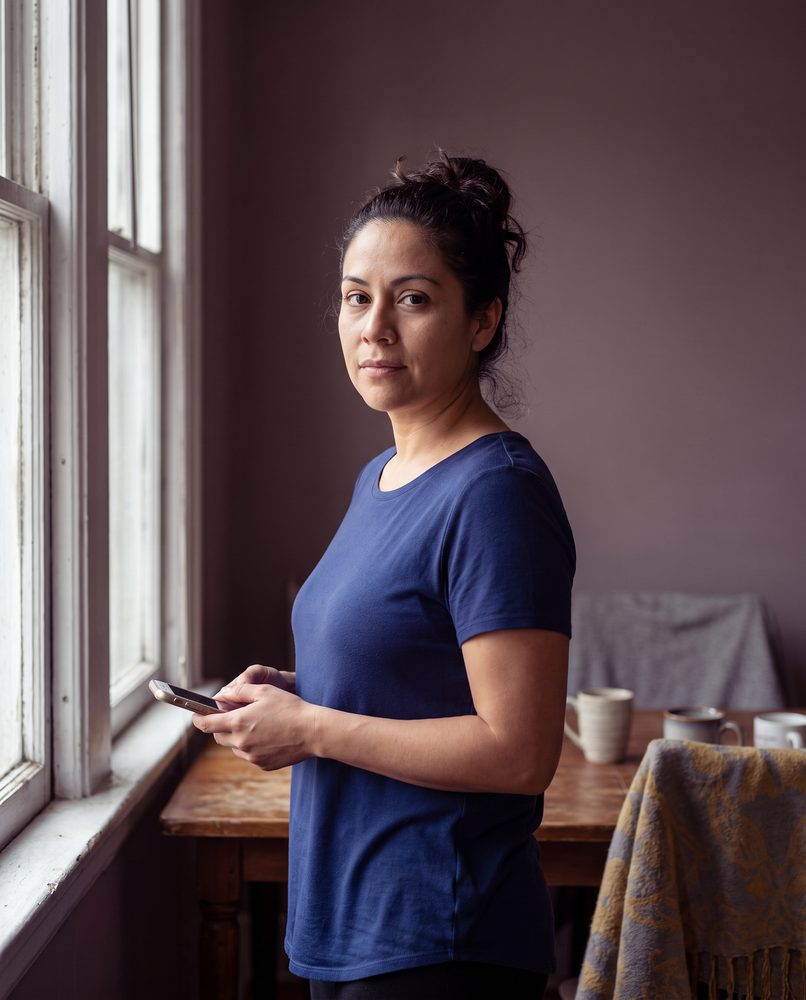 An actor standing calmly beside a window having just sent a finished self-tape