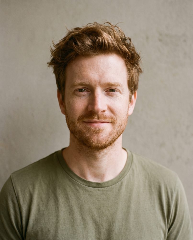 An actor standing against a plain wall, evenly lit, looking directly at the camera