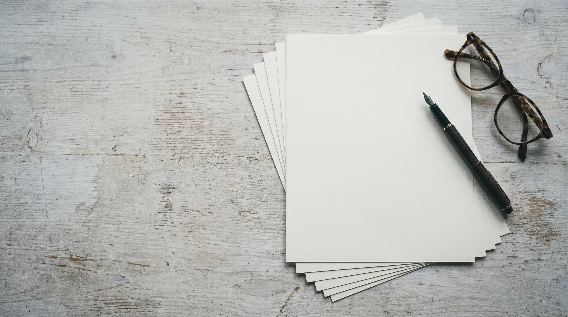 A multi-page printed contract on a pale table with a fountain pen and reading glasses